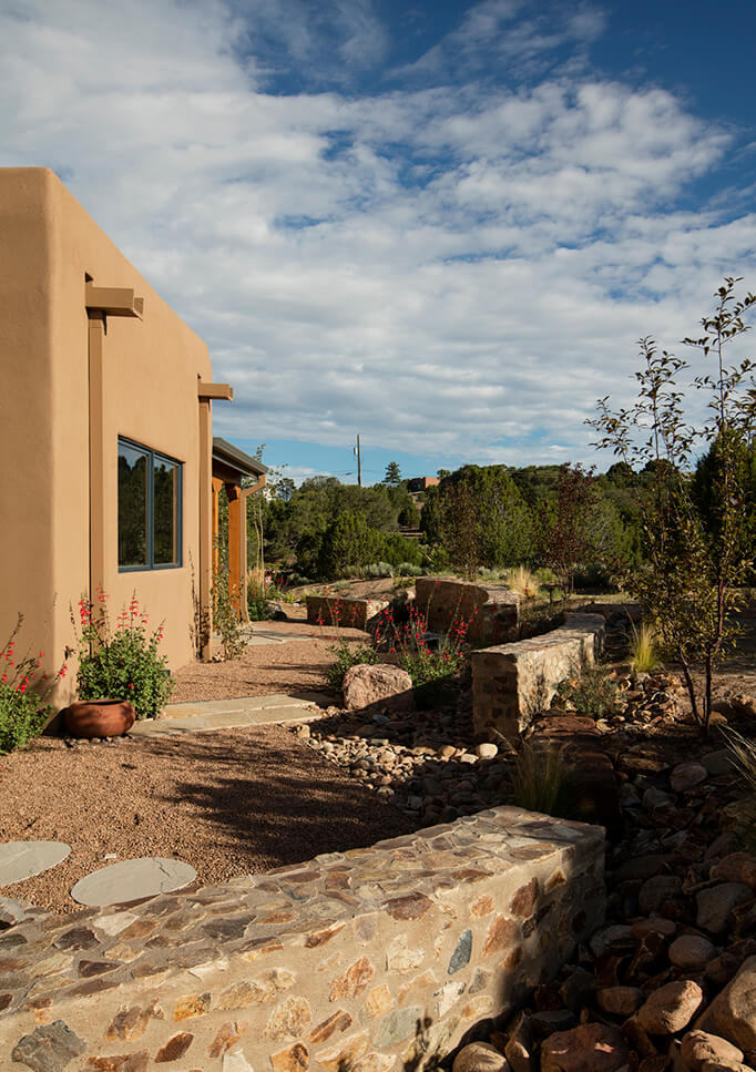 A Santa Fe style adobe house with a stone walkway expertly designed by a home designer.