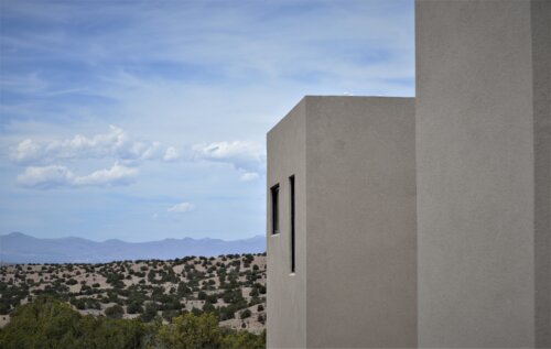 A building in the desert with a view of the mountains designed by an architect.