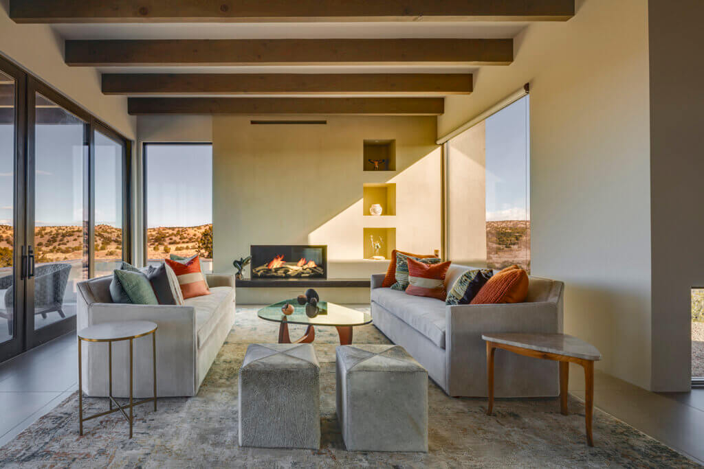 A Santa Fe style living room designed by an architect with a fireplace and a view of the desert.