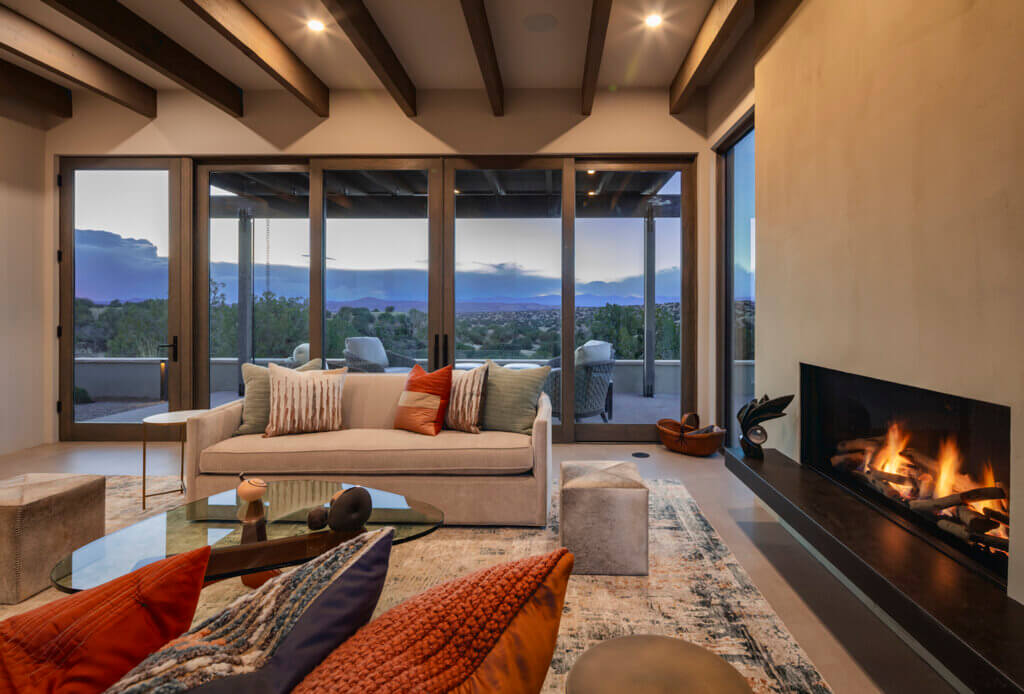 A Santa Fe-inspired living room with a fireplace and a breathtaking view of the mountains.