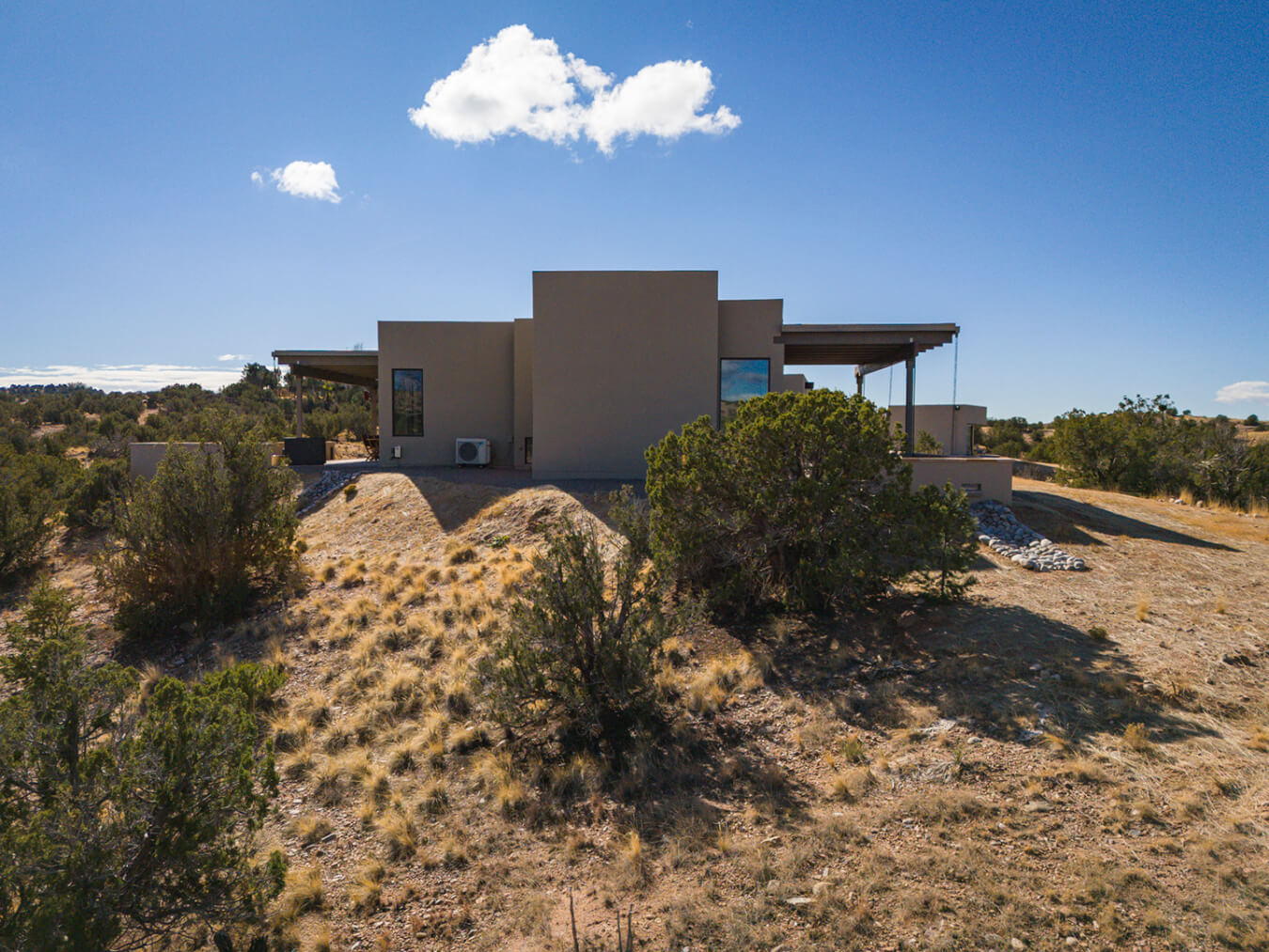 A Santa Fe-inspired house beautifully designed by an architect sits atop a hill in the desert.