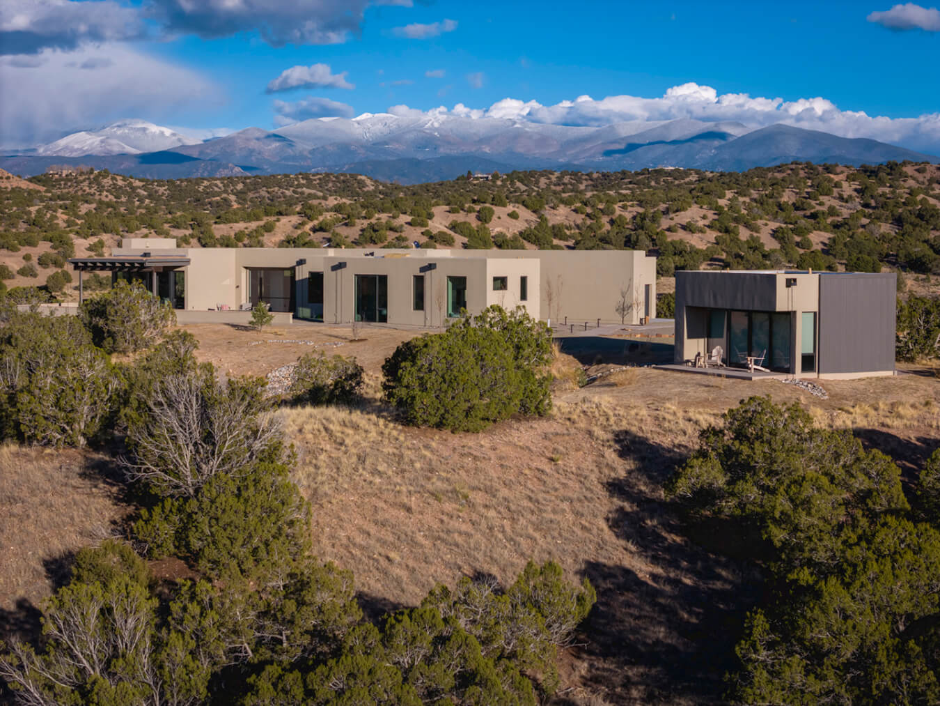 A modern Santa Fe-style home in the desert with mountains in the background.