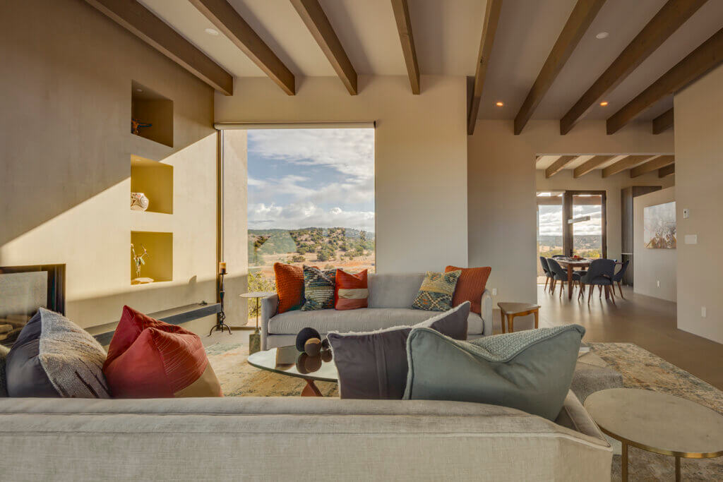 A Santa Fe living room with a view of the mountains, designed by a home designer.