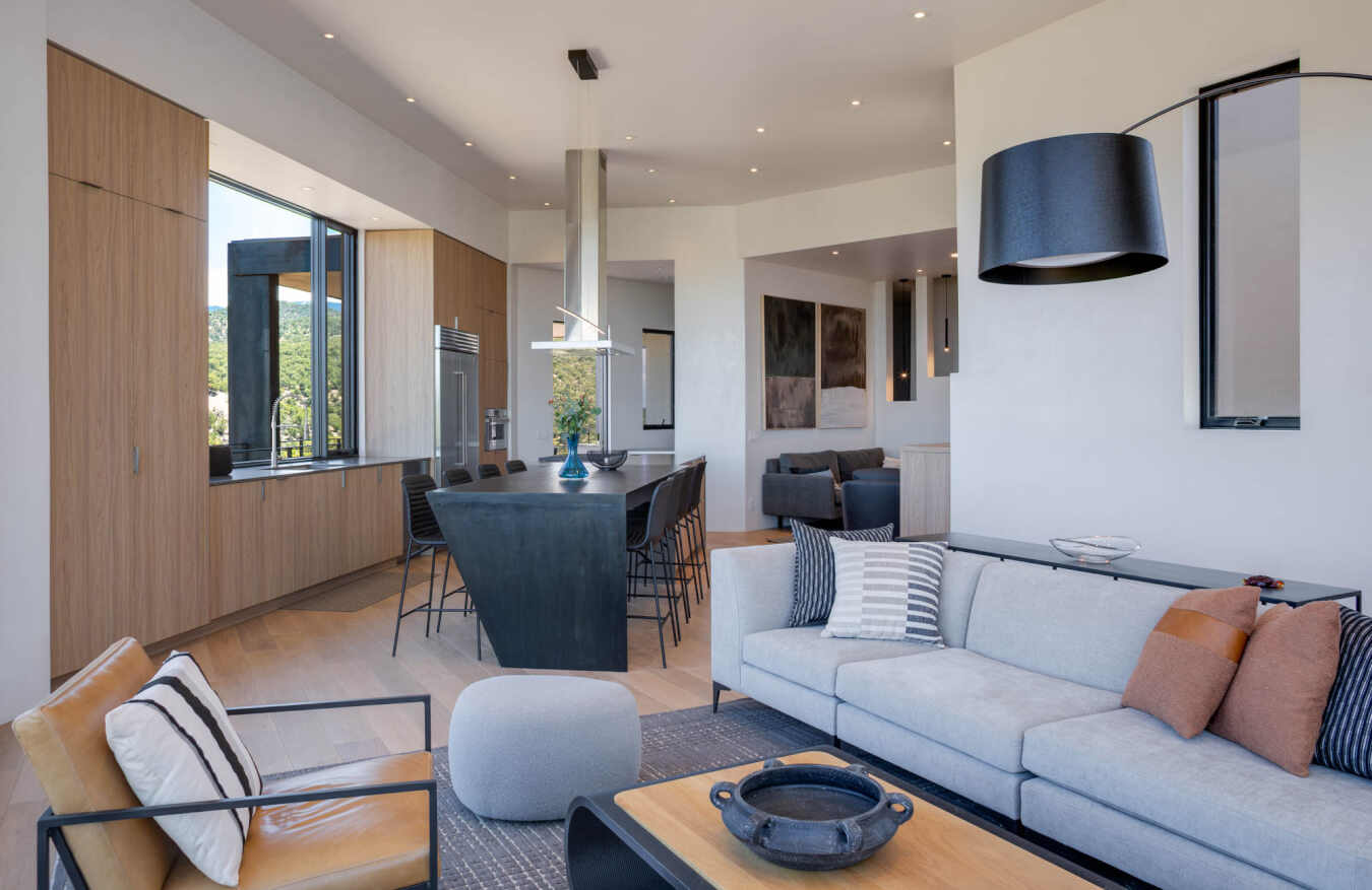 Modern open-concept living room and kitchen with neutral tones, contemporary furniture, large windows, and minimalist decor.